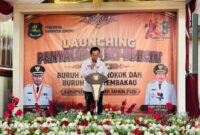 Kepala Dinsos P3A Kabupaten Sumenep Dr. R. Abd. Rahman Riadi SE MM Saat Membacakan Laporan dilaunching Penyaluran Bantuan Program BLT DBHCHT Tahun 2026 di Kecamatan Lenteng