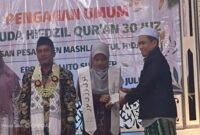 Direktur Rumah Khotmil Qur'an, Dr. Naghfir, S.H.I., S.H., M.Kn., menyerahkan uang pembinaan kepada wisudawan terbaik penghafal Al-Qur'an dalam Wisuda Tahfidz Pondok Tahfidzul Qur'an Maslahatul Hidayah, Kecamatan Bluto, Kabupaten Sumenep.